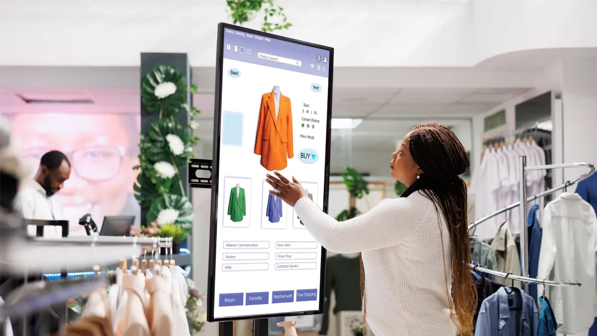 Interactive touchscreen displaying 3D clothing models in modern retail store with customer engagement