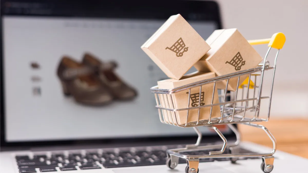 Mini shopping cart with packages on laptop keyboard representing current online shopping trends